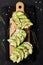 Bread slices with creamy cheese and avocado on wooden cutting board from above for healthy snack.