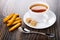 Bread sticks, teaspoon, tea in cup, sugar on saucer on table