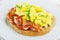 Bread toast with scrambled eggs, fried bacon and green onions close-up