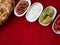 Bread, vegetables, sauces and snacks in plates on a red tablecloth, top view with empty copy space, background for menu