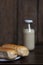 Bread on a white plate sits on a wooden board table with milk in a bottle behind it