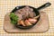 Breaded chicken liver with apple served in a frying pan, decorated with slices of apples and a sprig of parsley