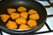 Breaded chicken nuggets are fried in a frying pan