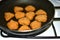 Breaded chicken nuggets are fried in a frying pan