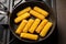 Breaded fish sticks in a frying pan. Preparation of frozen fish sticks. Fast food. Dark background