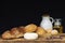 Breads, milk and oil on wood table with black background