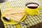 Breadsticks with filling, spoon in saucer, cup with tea on napkin on wooden table