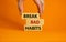 Break bad habits symbol. Wooden blocks with words `break bad habits`. Male hand. Beautiful orange background, copy space. Busine