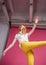 Break the rules. Attractive leggy blonde in yellow jeans poses in the studio on a pink background. Lower view