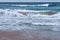 Breakers rushing onto the shore with spray and foam on a stormy day at the beach