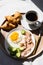 Breakfast in Bed Coffee Cup, Fried Egg, Bacon and Croissants on Wooden Tray. Trendy still life with interesting shadow.