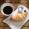 Breakfast with black coffee and a croissant with butter