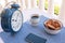 Breakfast or break outdoor on the balcony with coffe cup and chocolate biscuits.Big blue metal alarm clock. Cellphone and