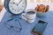 Breakfast or break outdoor on the balcony with coffe cup and chocolate biscuits.Big blue metal alarm clock. Cellphone and