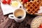 Breakfast with coffee and waffle, strawberries on brown wooden b