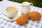 Breakfast composition of a cup of tea with cream, a creamer and sesame rolls