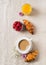 Breakfast concept with cup of coffee, croissants, berries, orange juice and flowers on cloth table