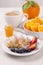 Breakfast with a cup of coffee, fresh croissant , jam and ripe strawberries and blueberries and juicy oranges on a white