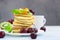 Breakfast with a cup of coffee and a stack of classic american pancakes served with black cherry, apricot, kiwi and mint. Blue