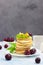 Breakfast with a cup of coffee and a stack of classic american pancakes served with black cherry, apricot, kiwi and mint. Blue