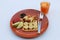 Breakfast in the dark orange color of round plate on the white floor. Dough roll and banana on the waffle and fruit rose apple,