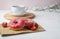 Breakfast with delicous donuts with strawberry frosting and black coffee