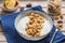 Breakfast or dessert, unsweetened yogurt with granola, dark chocolate, hazelnuts and sliced banana in a ceramic bowl on a wooden