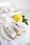 Breakfast eclairs with white porcelain dishes and a yellow flower on the table