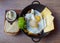 Breakfast, eggs, cheese, potatoes, butter, bread and salad in a frying pan on a wooden tray