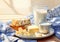 Breakfast with flakes, milk, coffee, toast, cheese and butter on a table with tablecloth with blue and white squares.