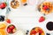 Breakfast frame of fruits, cereal, waffles, yogurt, milk and coffee. Top view over a white wood background.