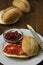 Breakfast with fresh buns and butter, strawbery jam on wooden background. Vertical image