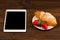 Breakfast with fresh croissants, fresh strawberry on a rustic wooden background, top view. tablet pc.