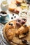 Breakfast with fresh croissants, fruits,coffee,muffins and chocolate paste on white wooden table.