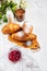 Breakfast with fresh croissants, glass of coffee, milk, strawberry jam and flowers on a white wooden background