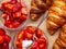 Breakfast with fresh croissants, strawberry with cream in glass bowls background