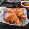 Breakfast with fresh french chocolate croissants on paper over dark background with napkin and cup of tea. Dessert, puff pastries