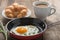 Breakfast fried egg in pan with coffee, croissant.