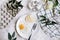 Breakfast of fried egg and pear on a white plate with a fork. In a glass bowl, yogurt and a dragon fruit, next to a tray of quail