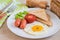 Breakfast with fried egg, toast, sausage and vegetable on table