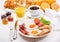 Breakfast with fried eggs, croissants, juice, coffee and fruits