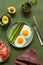 Breakfast fried eggs with fresh asparagus and ham (jamon), herbs in a plate on green background.