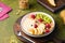 Breakfast, granola with yogurt, pear, kiwi and raspberries in a flat white plate on a green concrete background. Healthy quick