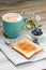 Breakfast idea. Cup with coffee with blueberries, flowers and toast on linen napkin