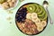 Breakfast with muesli, acai blueberry smoothie and kiwi, banana, fruits on green background. Healthy food concept