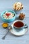 Breakfast: oatmeal with fruit pieces and candied strawberries, honey, pear and apple chips in small bowls and a cup of black tea