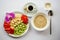 Breakfast of oats, a plate of fruit decorated with a orchid, yogurt and coffee on a white background. Flat lay. View