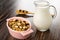 Breakfast with peanut and raisin in bowl, transparent pitcher with yogurt, spoon with granola on wooden table