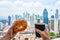 Breakfast in a picturesque place. Man holds in his hand a cup of coffee and a croissant on the balcony of a skyscraper with a view