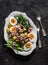 Breakfast plate - boiled eggs, potatoes, string beans, red onion, cucumber, canned tuna salad on a dark background, top view